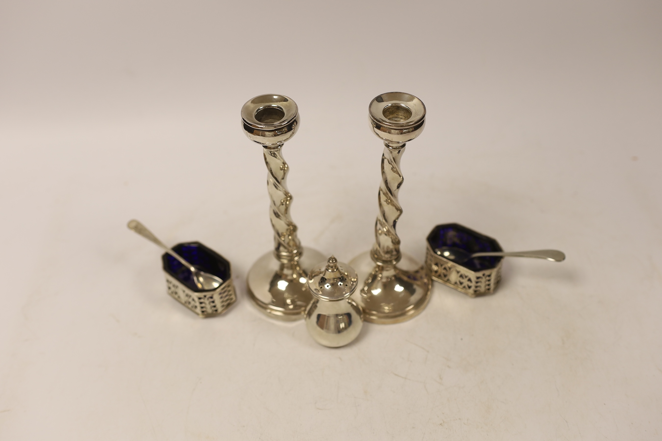 A pair of silver mounted candlesticks, marks rubbed and three silver condiments with two spoons, one plated. etc. (4)